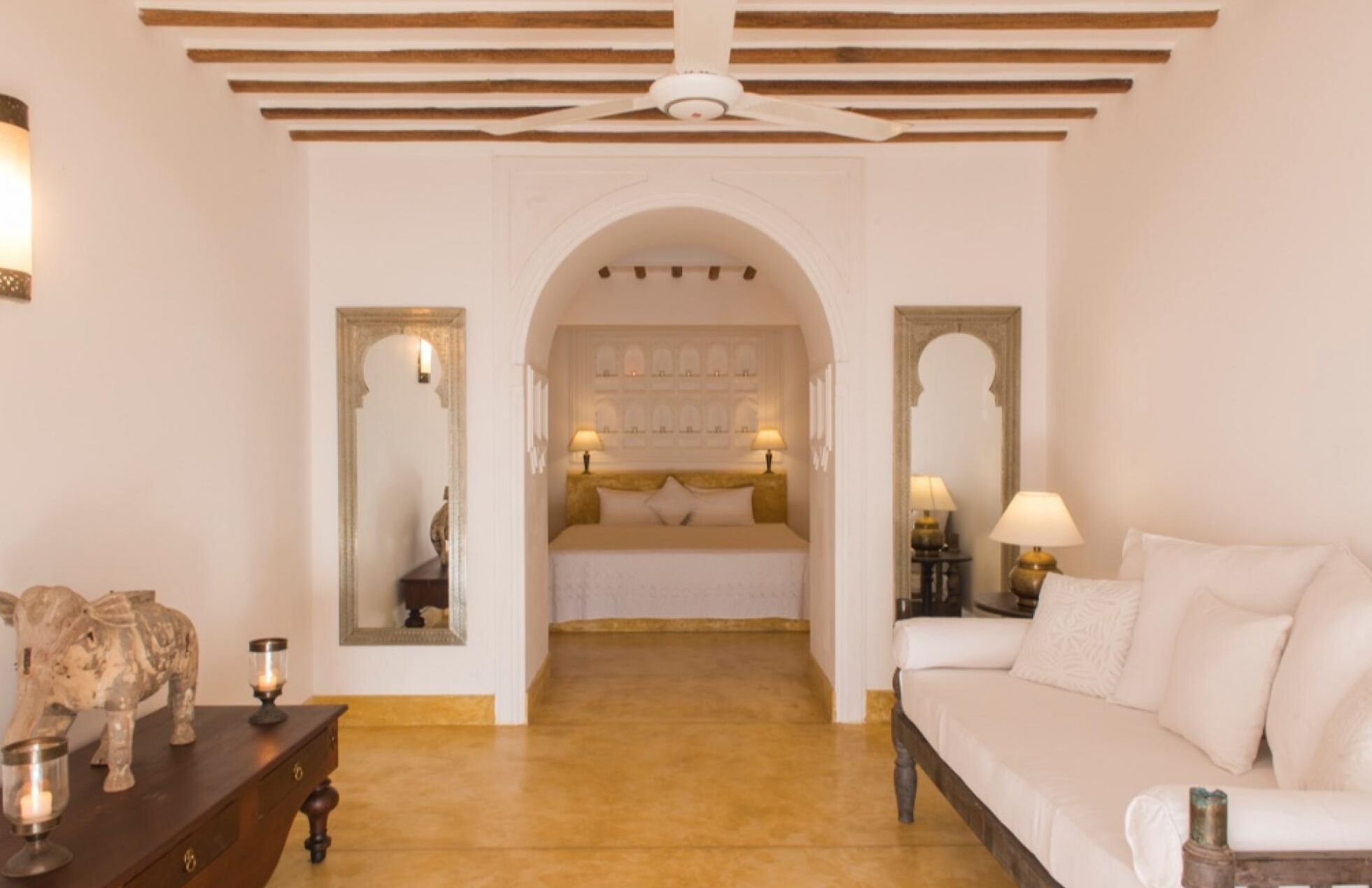 Habitación de hotel con una cama, un sofá, una escultura decorativa de elefante y un espejo.