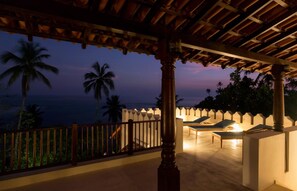 A covered outdoor area with lounge chairs and a view of the ocean at dusk. - Celadon House in Weligama (Weligama)