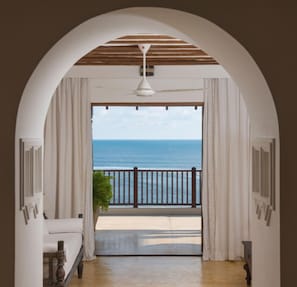 Enjoy the ocean view from the comfort of your room, featuring a bed, balcony, and ceiling fan.