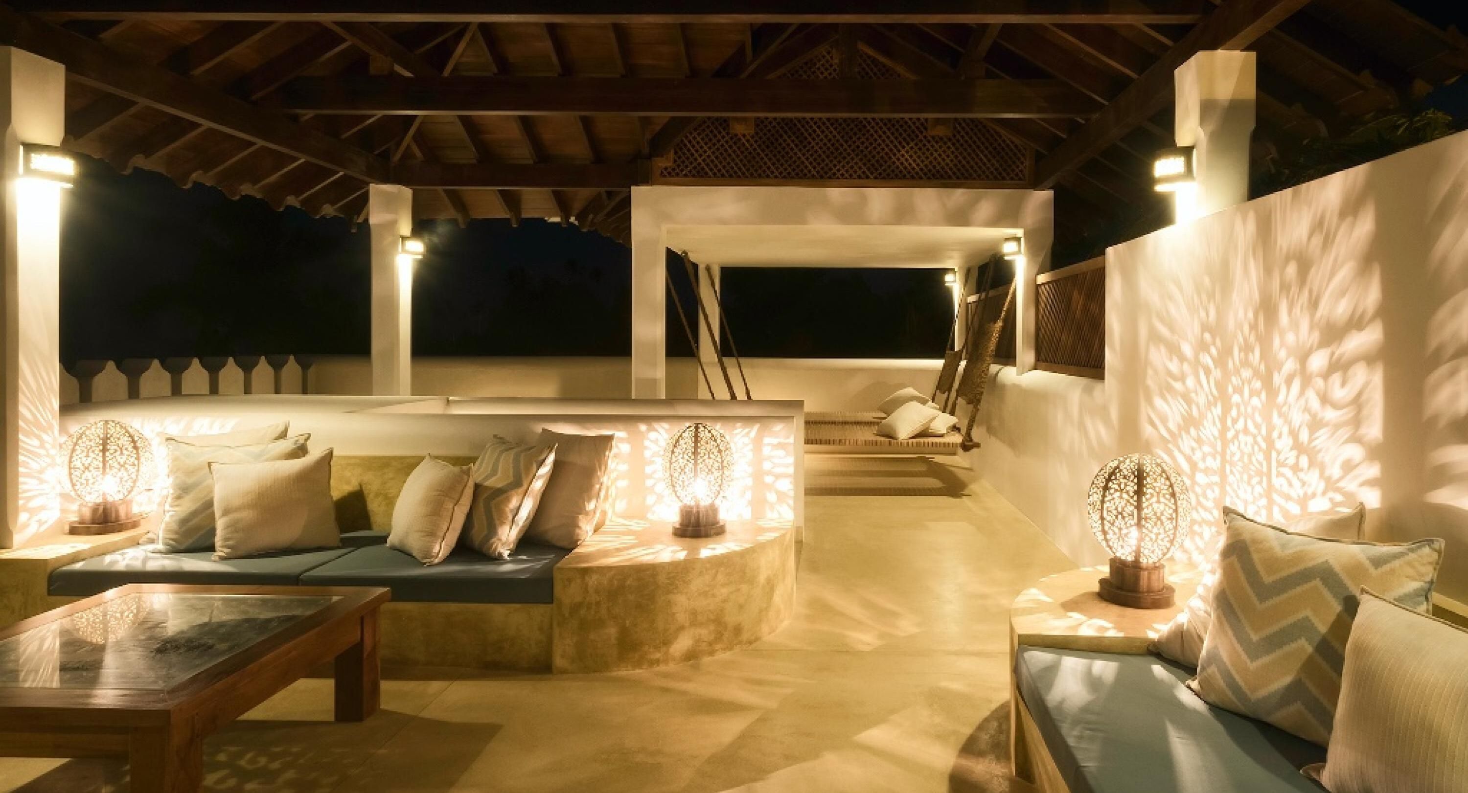 A well-lit outdoor lounge area with seating arrangements and a view of the night sky.