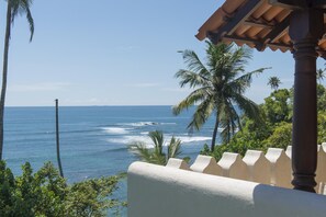 Enjoy breathtaking ocean views from this balcony, surrounded by lush greenery and palm trees.