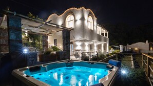 A hot tub with a stone wall and a covered patio area. - Villa Olivella by Elite Villas (Anacapri)