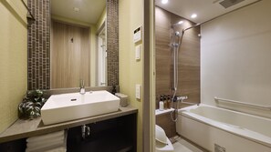 A modern bathroom with a large sink, a shower, and a mirror.