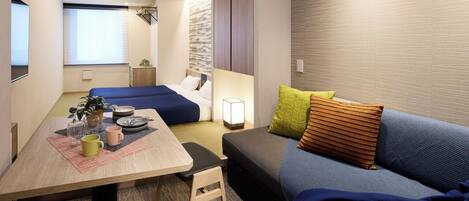 A compact hotel room with a dining area, a sofa, and a bed.