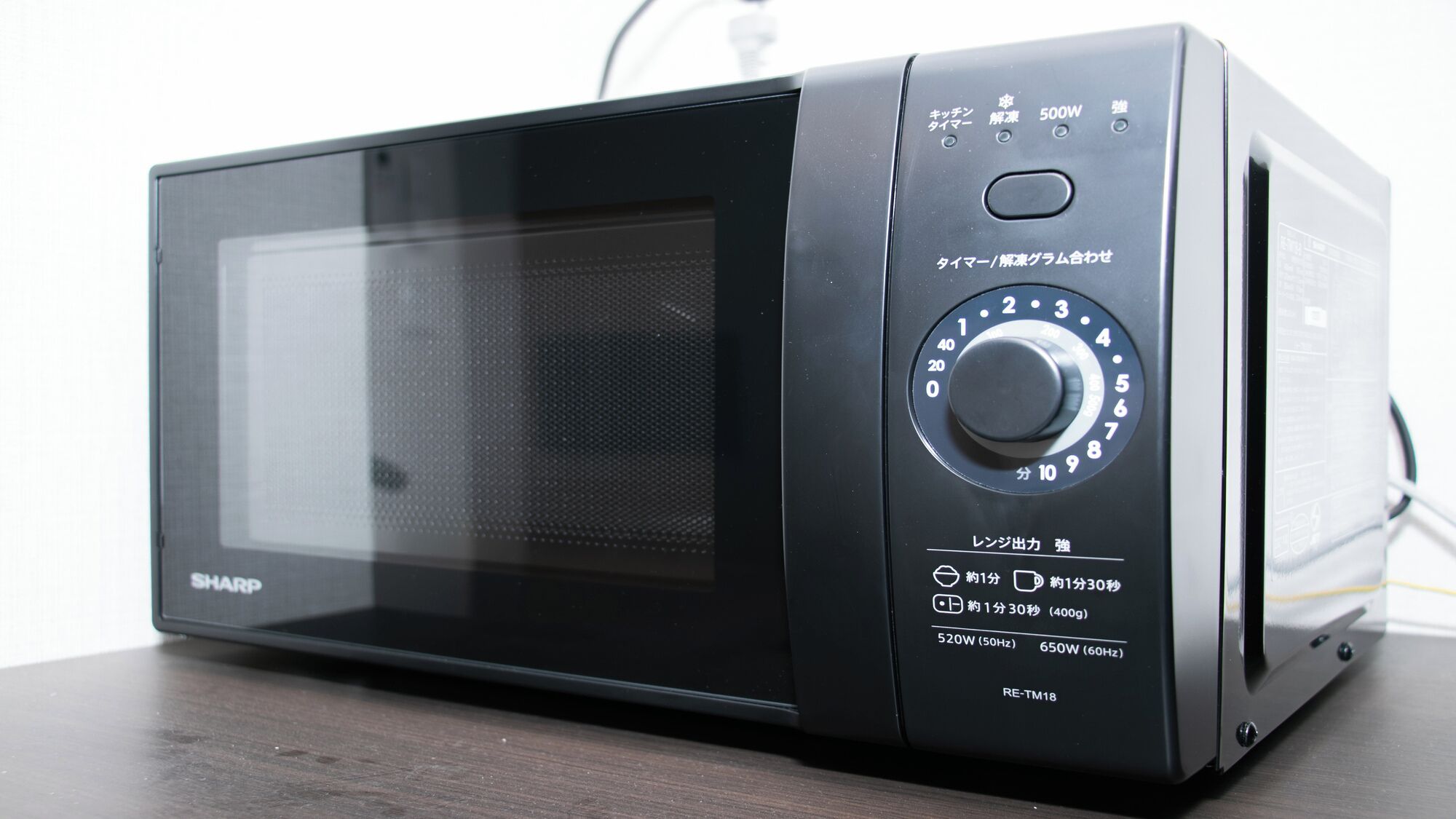 A Sharp microwave oven with a digital display, power buttons, and a dial for setting the time.