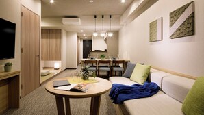A modern living room with a sofa, a coffee table, and a TV. There is a dining area with a table and chairs. - Minn Ueno Shin-Okachimachi (Tokyo)