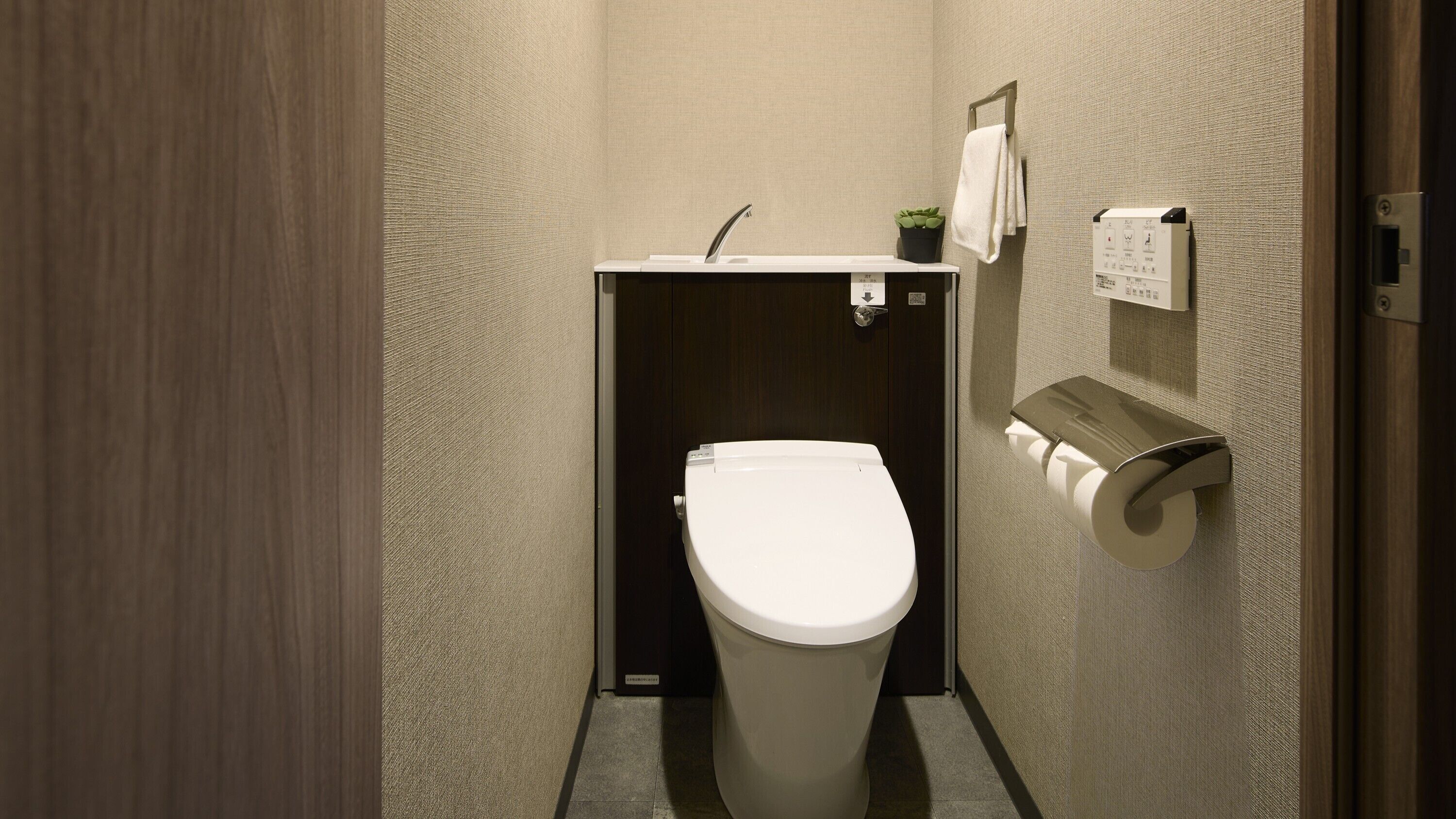 Ein kleines, modernes Badezimmer mit Toilette, Waschbecken und Handtuchhalter.