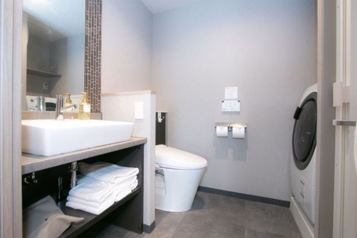 A modern bathroom with a sink, toilet, and washing machine.