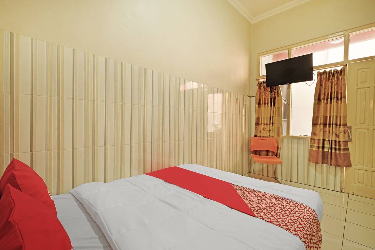 Une chambre d’hôtel avec un lit, une télévision et des rideaux.