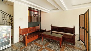 Una habitación con un banco de madera, una mesa con superficie de vidrio y un suelo estampado.