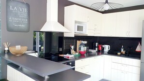 A modern kitchen with white cabinets, a black countertop, and a stainless steel range hood.