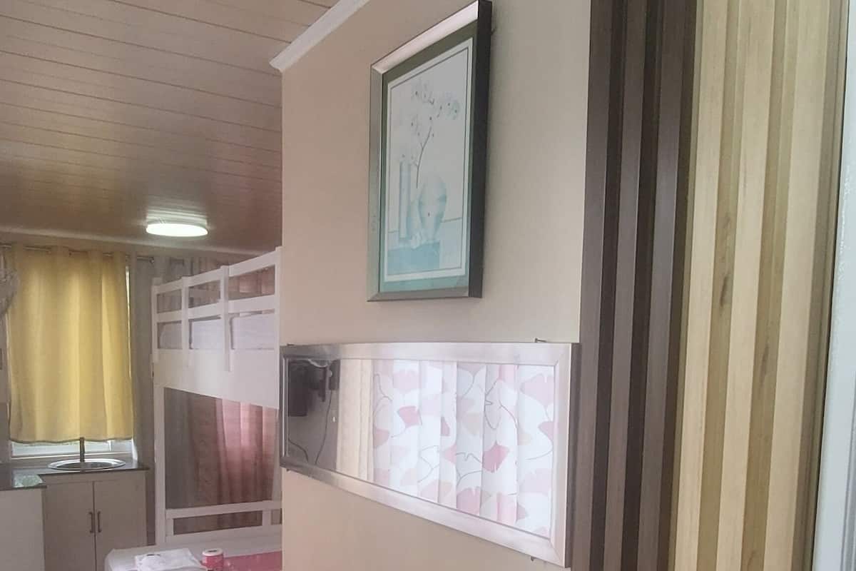 A hotel room with a bunk bed, a small desk, and a window with curtains.