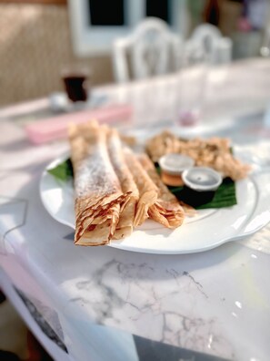 Un plato de crepas sobre una mesa blanca con diseño de mármol.
