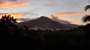 Une montagne dont le sommet est enveloppé de nuages, entourée d’une végétation luxuriante.
