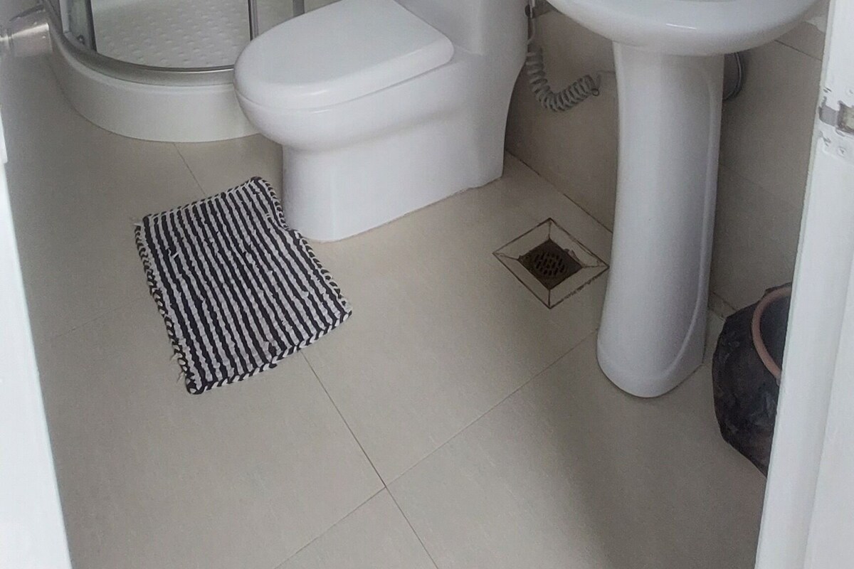 Un baño con ducha de vidrio, inodoro y lavamanos con espejo superior.