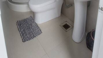 Un baño con ducha de vidrio, inodoro y lavamanos con espejo superior.