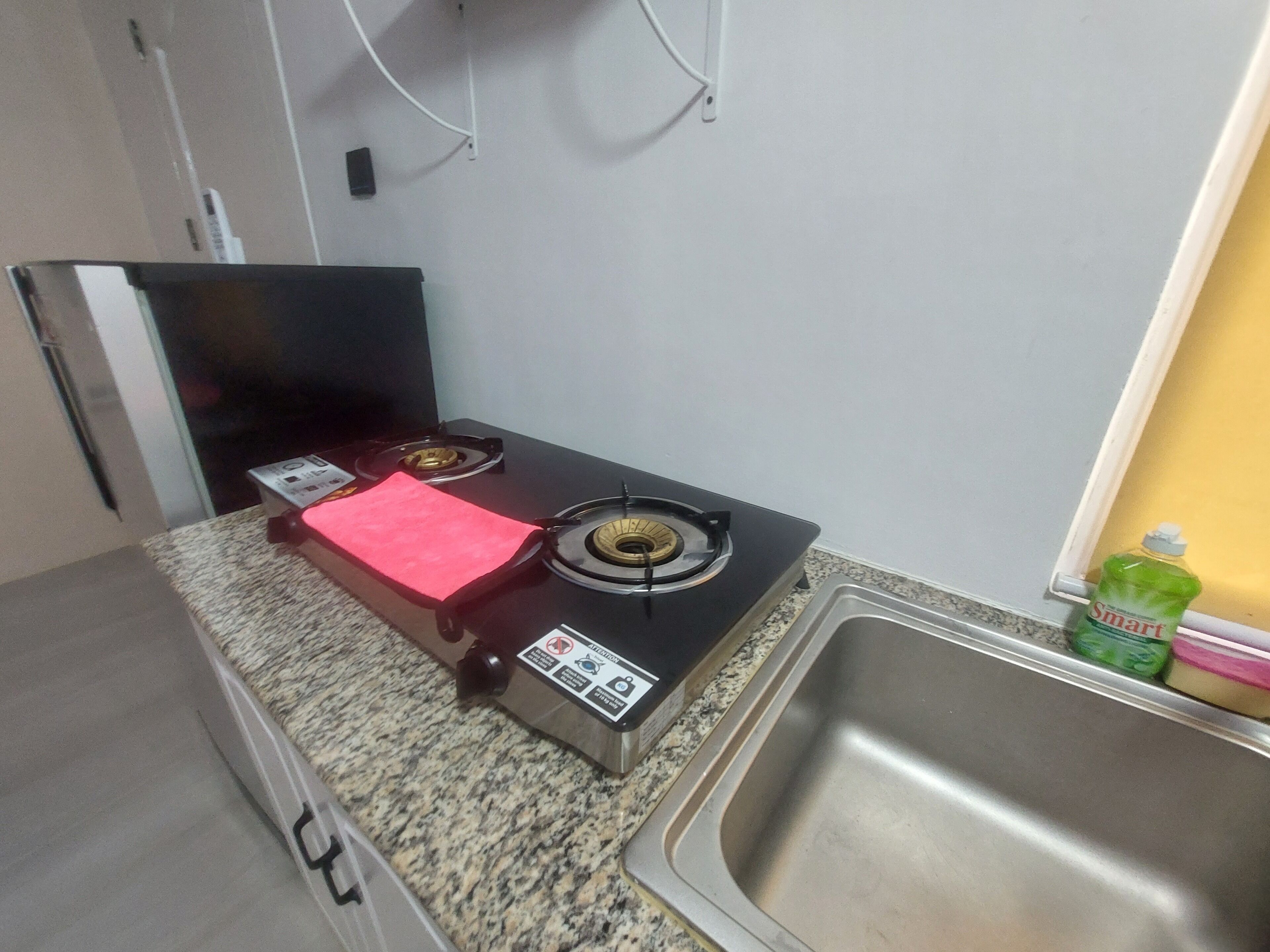 Een keuken met een gasfornuis, een roestvrijstalen spoelbak en een granieten aanrecht.