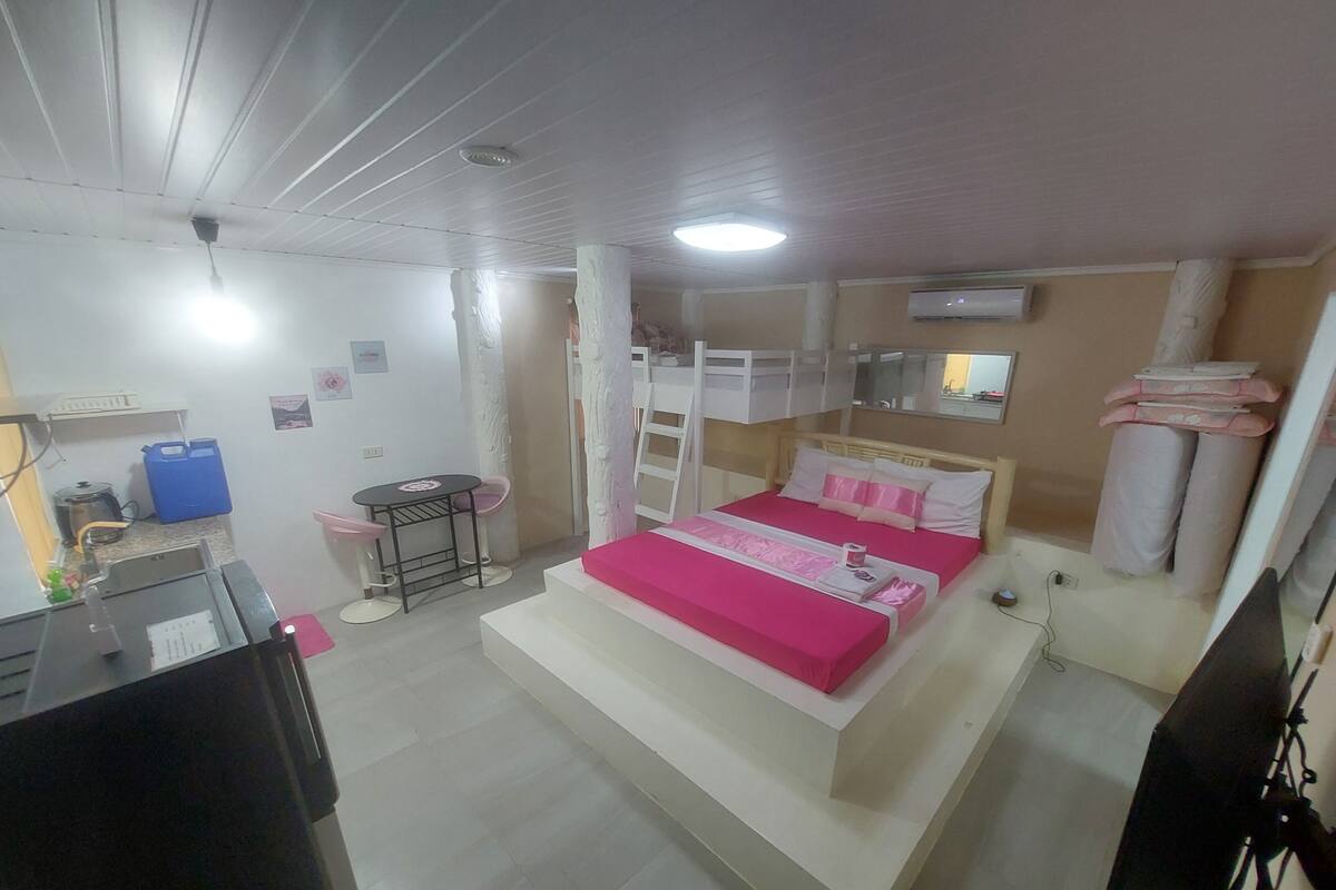 A bedroom with bunk beds, a desk, a chair, and a small table.