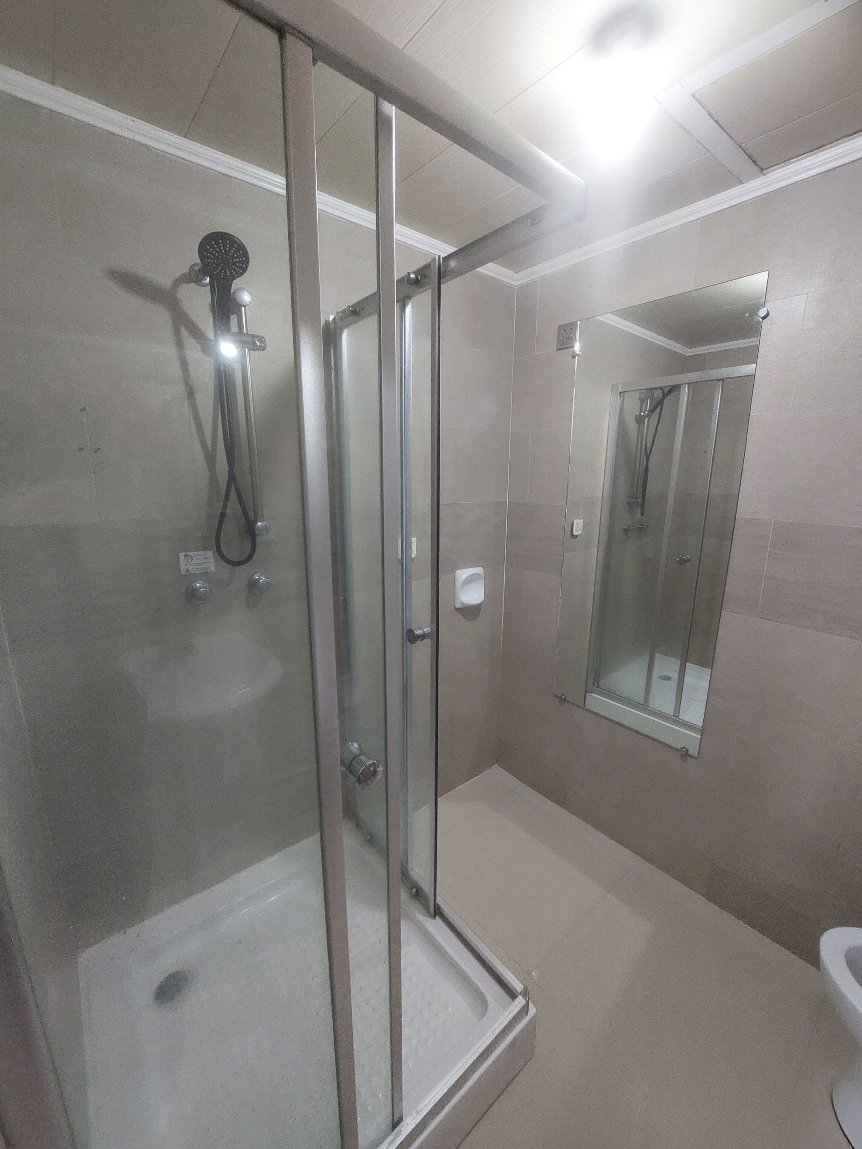 Un baño moderno con ducha de vidrio, inodoro y espejo.