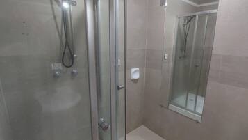 Un baño moderno con ducha de vidrio, inodoro y espejo.