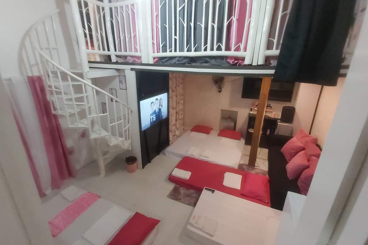 A room with a bunk bed, a TV, a desk, and a chair.