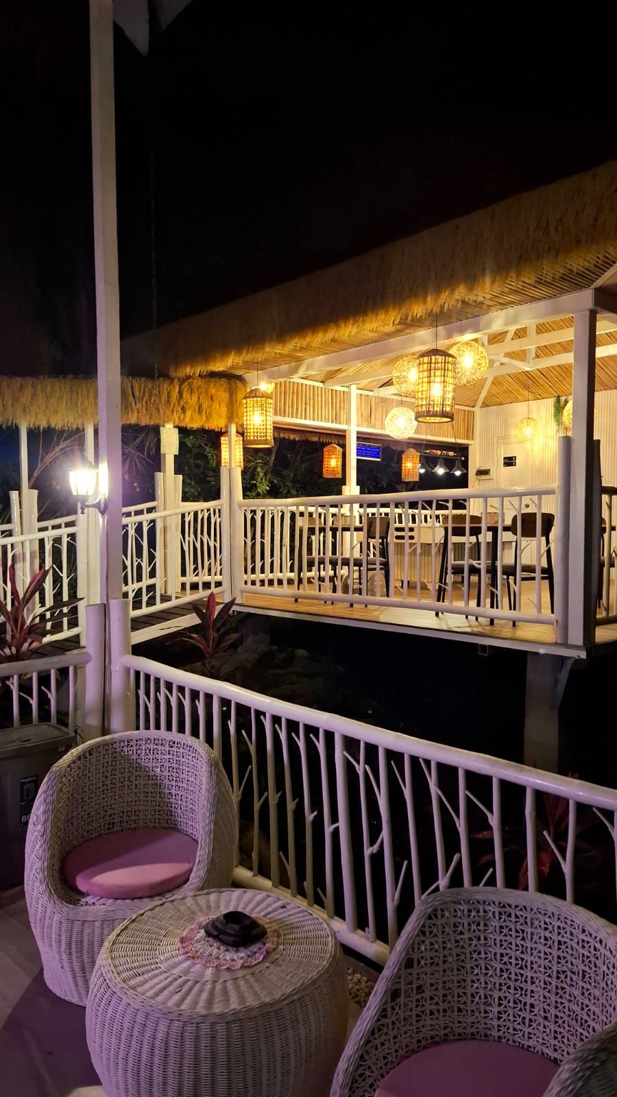 An outdoor bar area with wicker furniture and a thatched roof.
