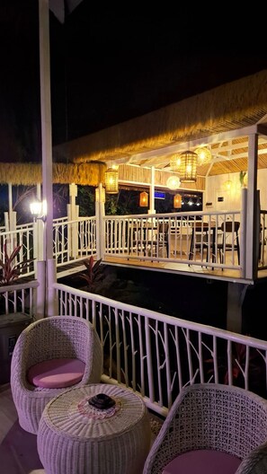 An outdoor bar area with wicker furniture and a thatched roof. - A touch of pink secret garden resort (Puerto Princesa)