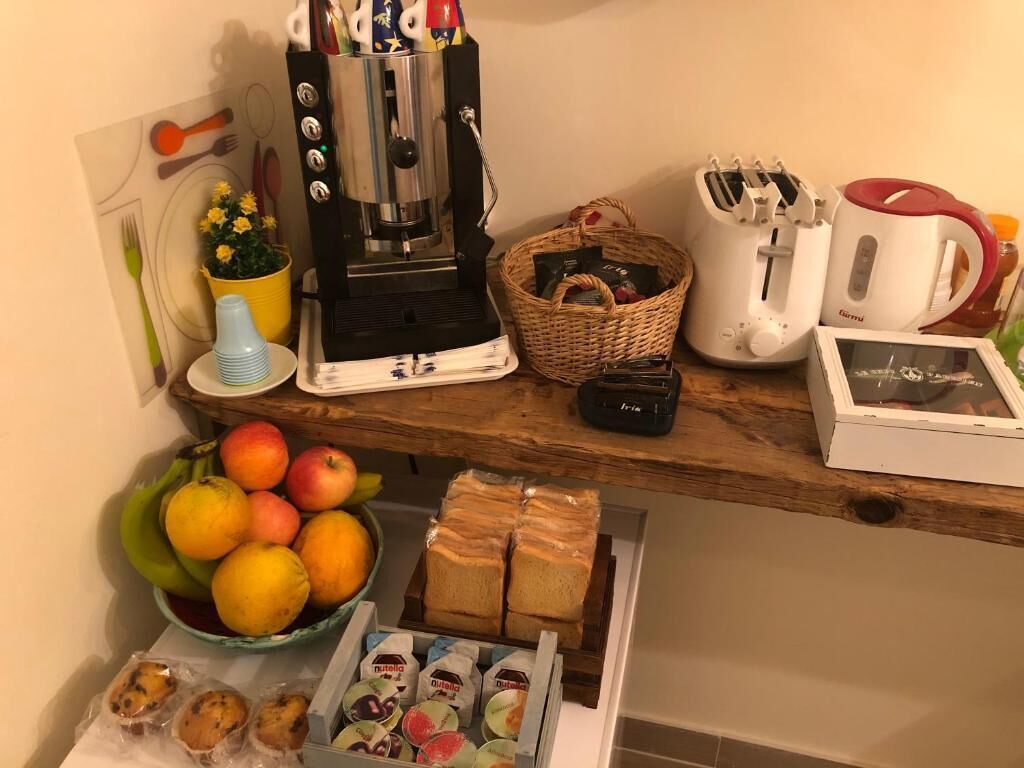 A kitchen counter with a coffee maker, toaster, mug, basket, and a bowl of fruit and bread.