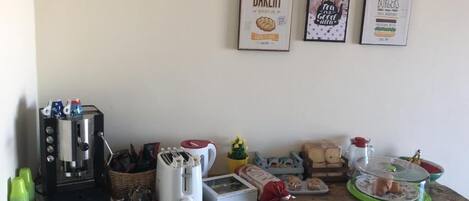 Una encimera de cocina con una cafetera, un tostador y diversos alimentos.