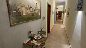 A hallway with a dining table set up, a painting on the wall, and a door at the end. - Pompei Window (Pompei)