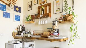 A compact kitchen with a refrigerator, wooden shelves, and various kitchen items. - Pompei Window (Pompei)