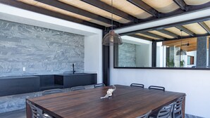 Un comedor moderno con una mesa y sillas de madera, un colgante de luz y una pared de piedra.