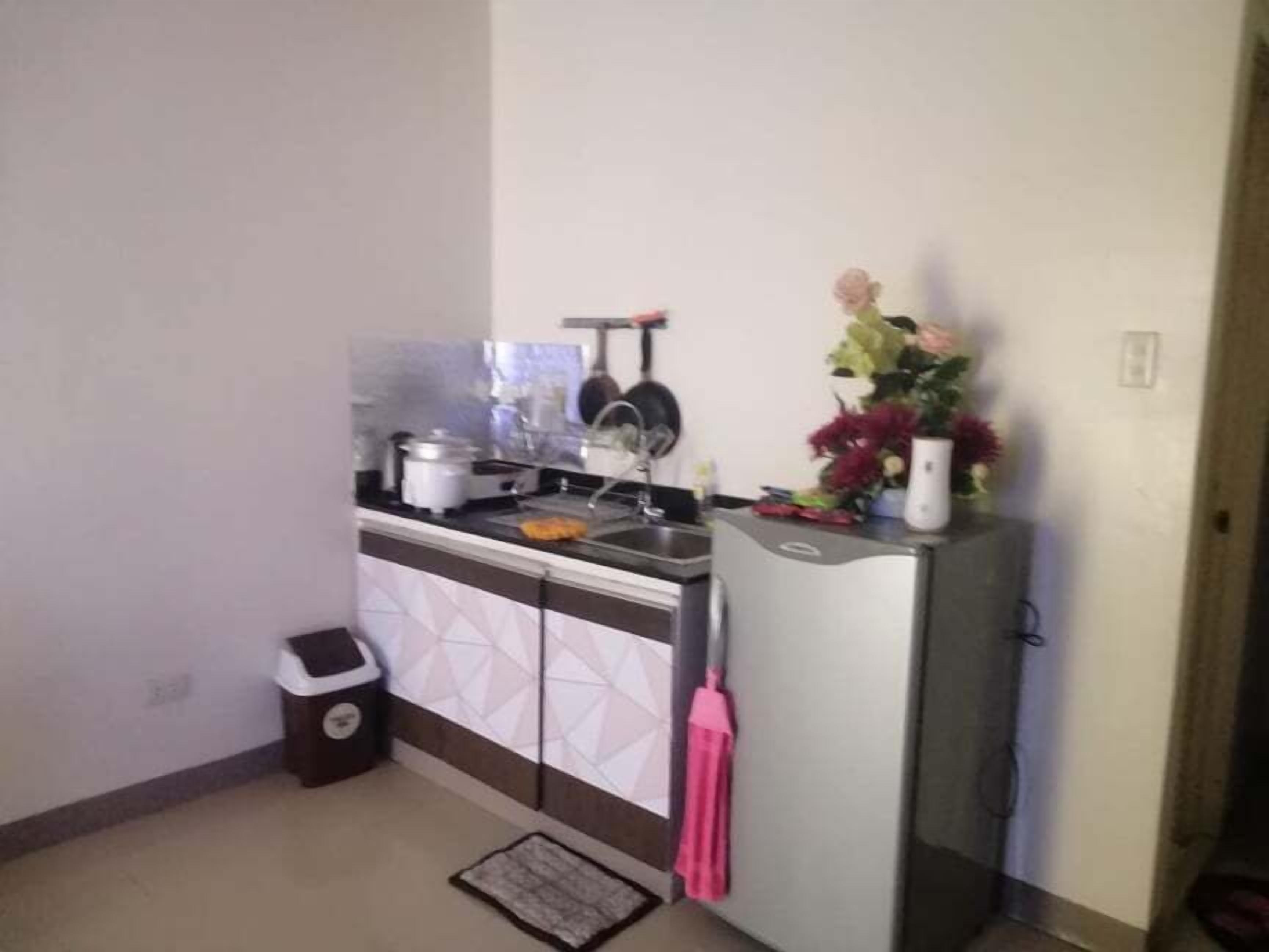 Een kleine keuken met een spoelbak, fornuis en een klein prullenbakje.