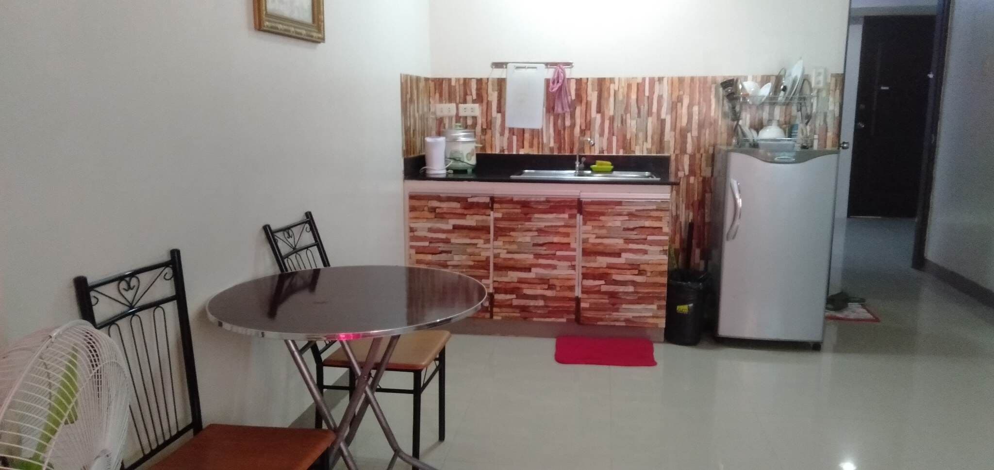 Una cocina compacta con una mesa y sillas, un refrigerador y una pequeña encimera con un lavabo.