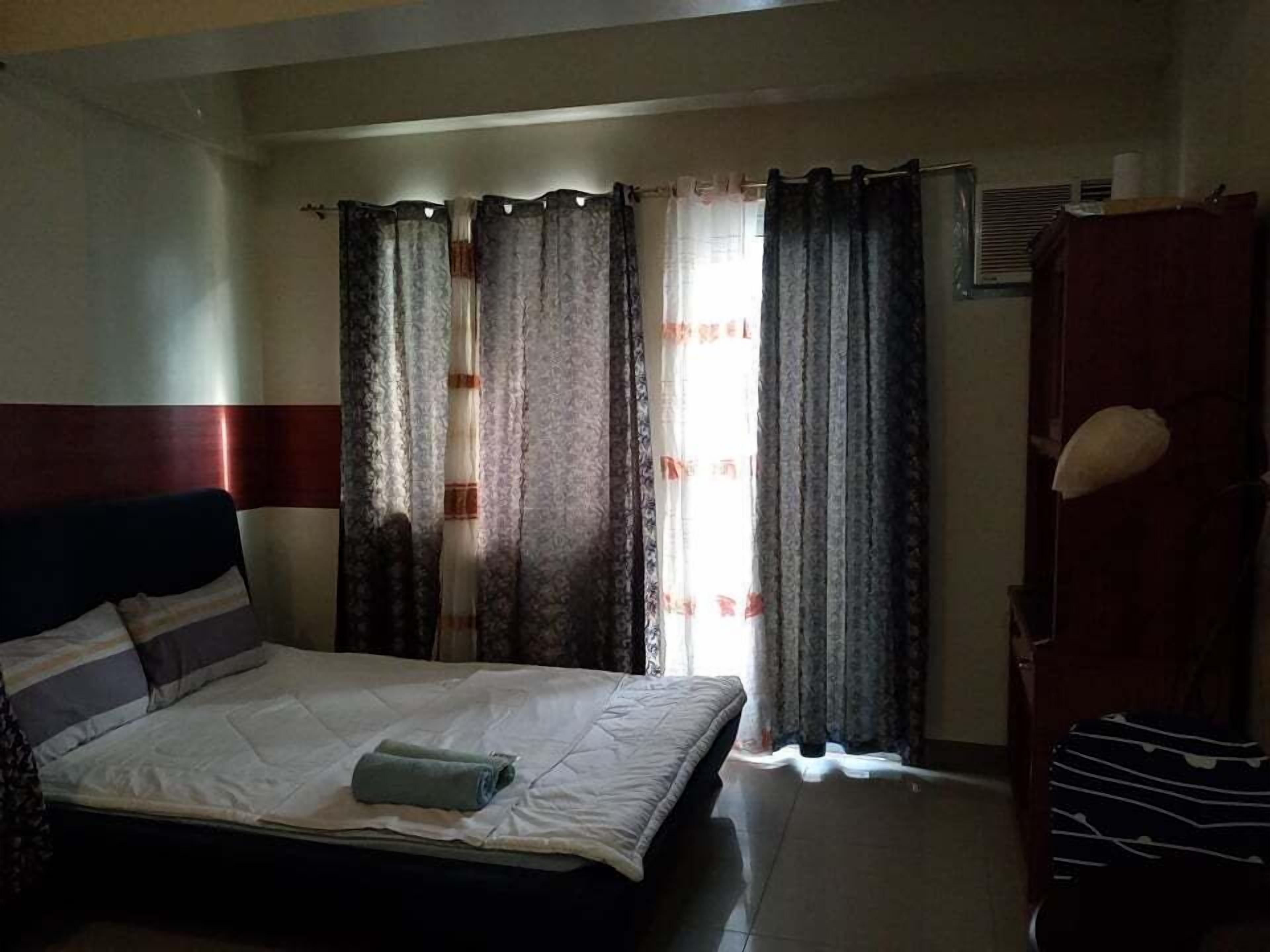 Un dormitorio con cama, cortinas, un armario de madera y un radiador.