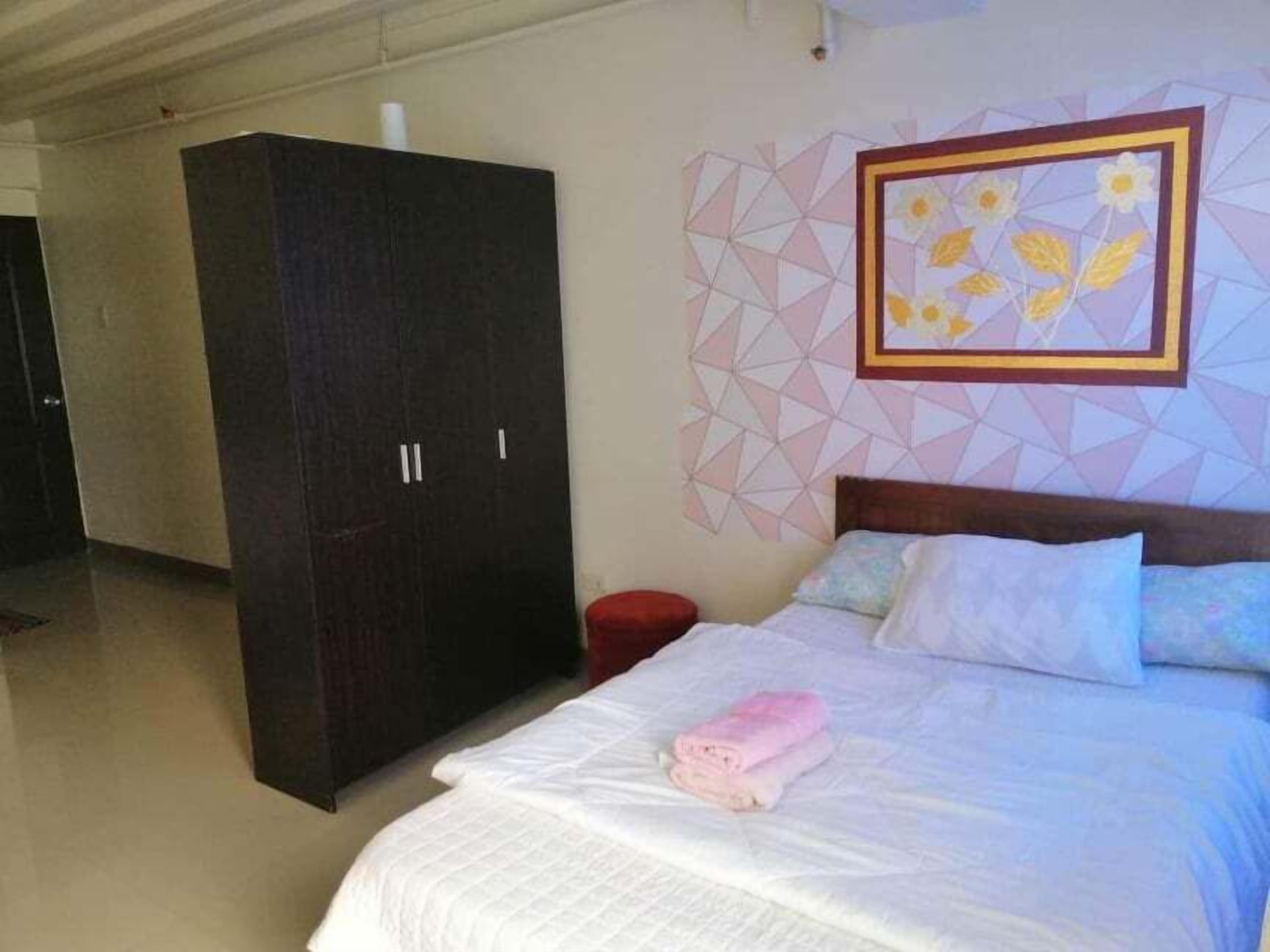 A hotel room with a bed, a wardrobe, and a geometric-patterned wall.