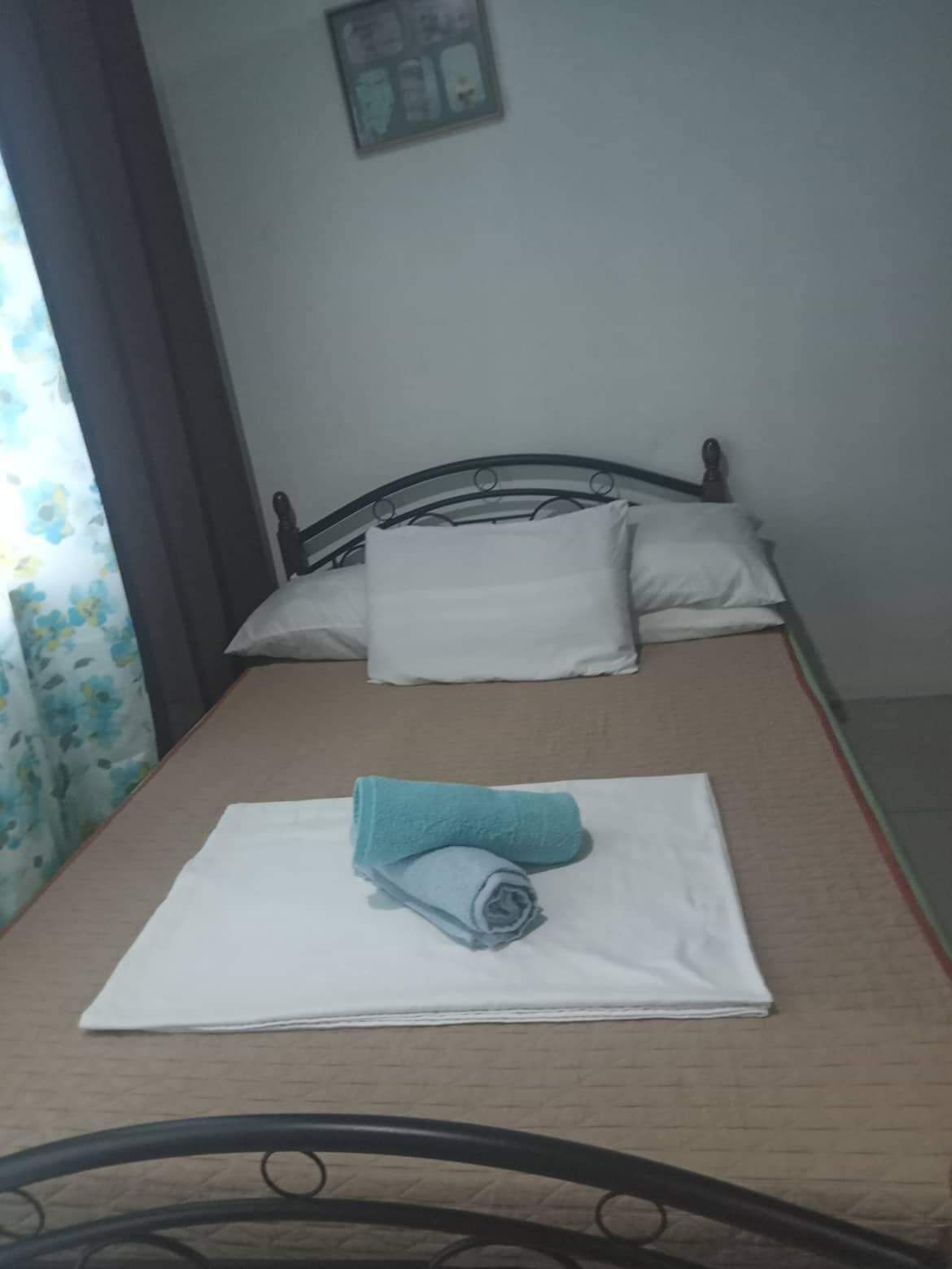 Una cama individual con un colchón blanco, una toalla azul y una almohada blanca.