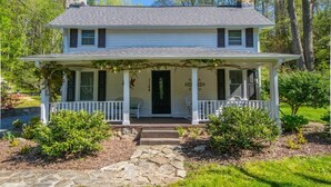 A two-story house with a front porch, stone steps, and a small garden.