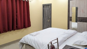 A bedroom with a bed, a wardrobe, a door, and an air conditioning unit.