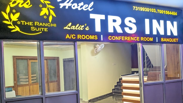 A hotel named TRS INN with a signboard indicating A/C rooms, a conference room, and a banquet.