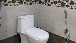 A bathroom with a toilet, a shower, and a mosaic tile border.