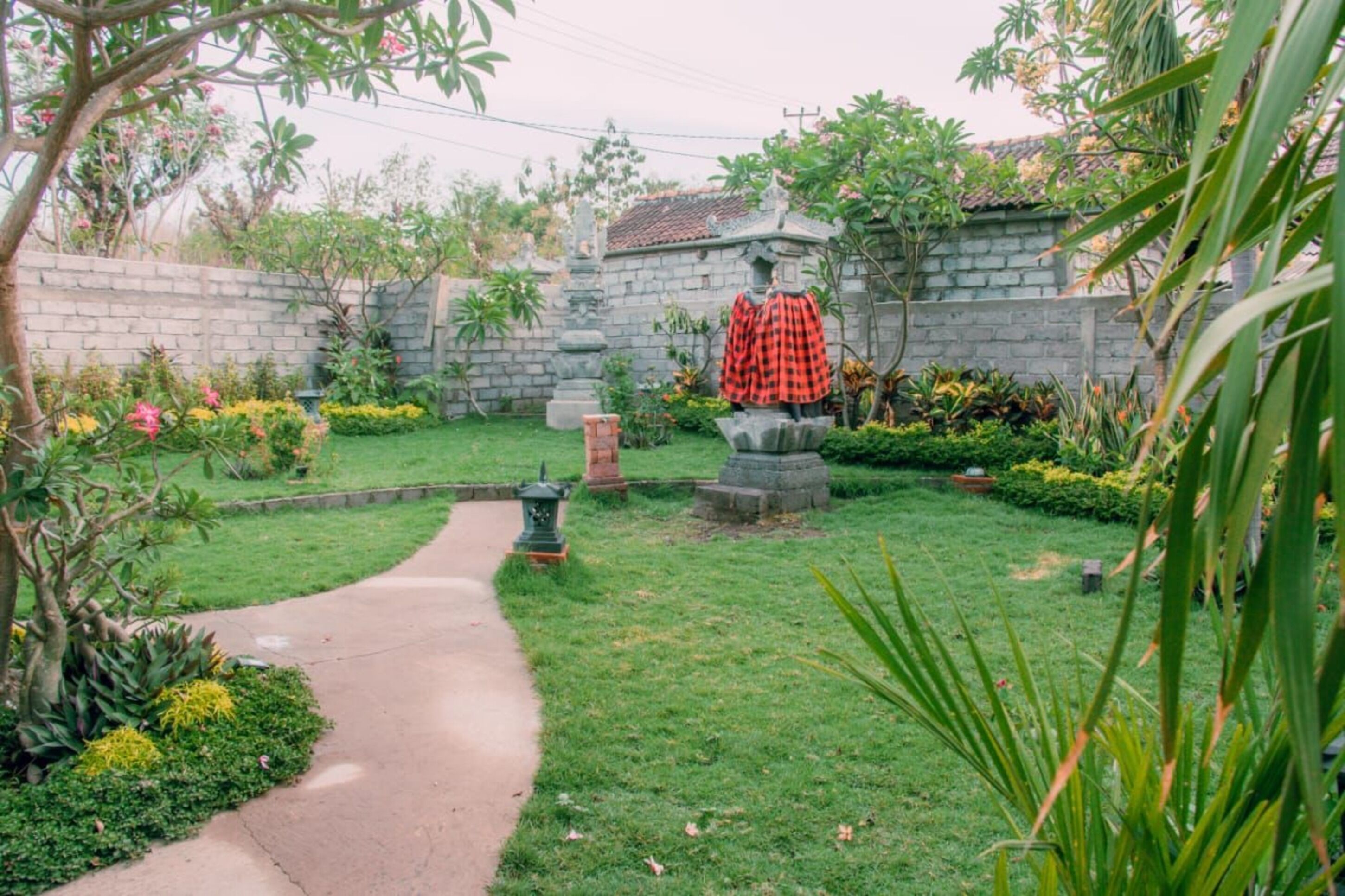 A garden with a paved path, a statue, and various plants.