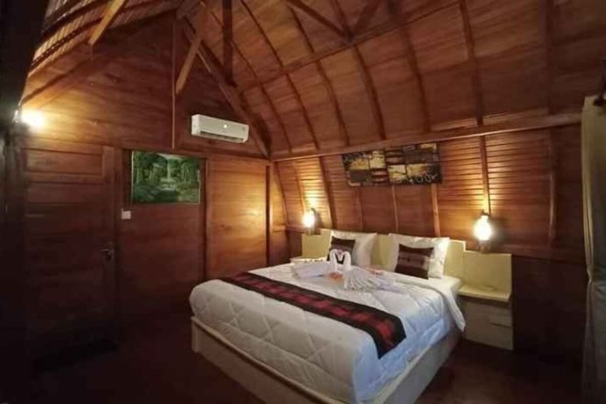 Een houten kamer met een bed, bedlampen en een wandairconditioner.