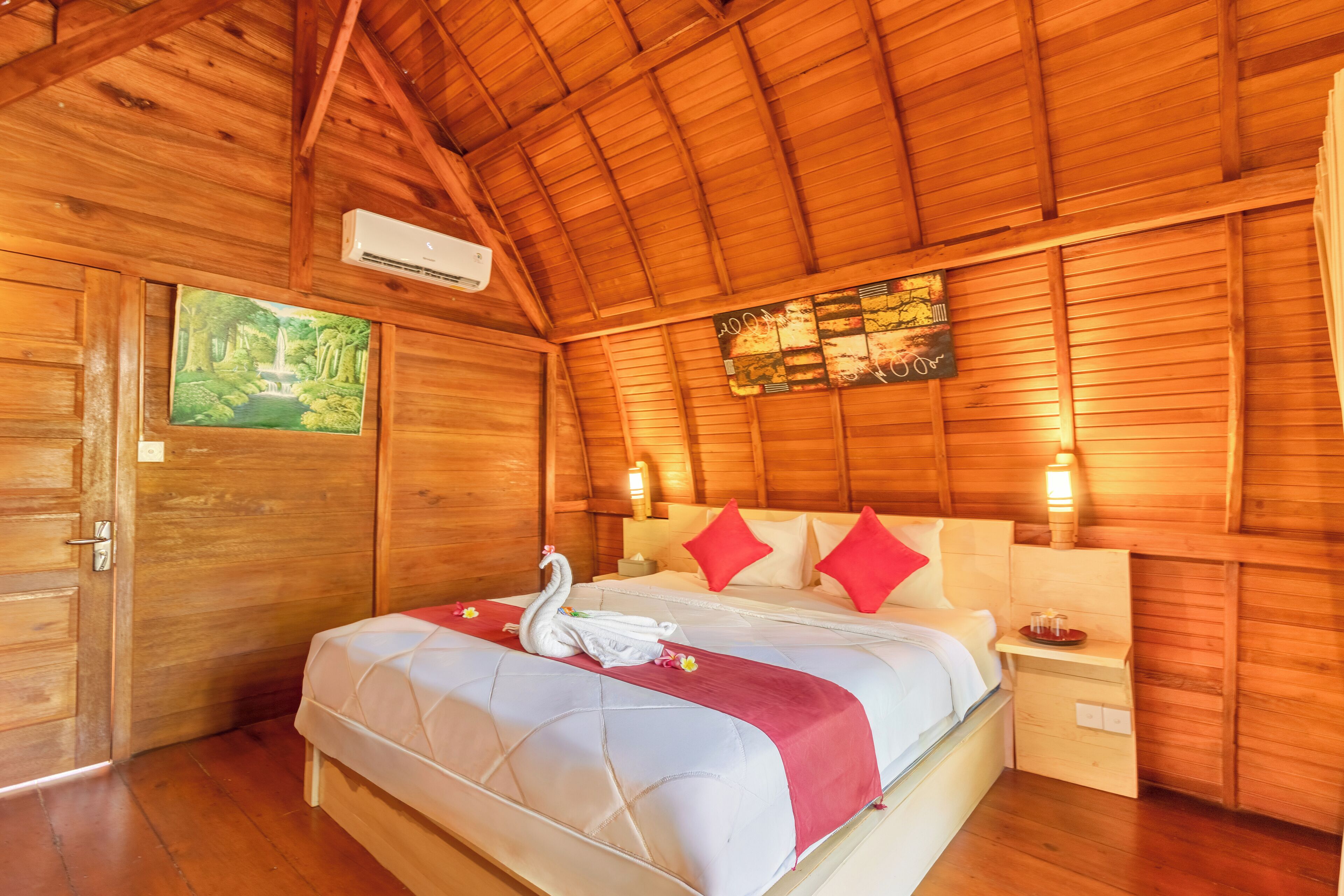 A wooden room with a bed, a painting, and a wall-mounted air conditioner.