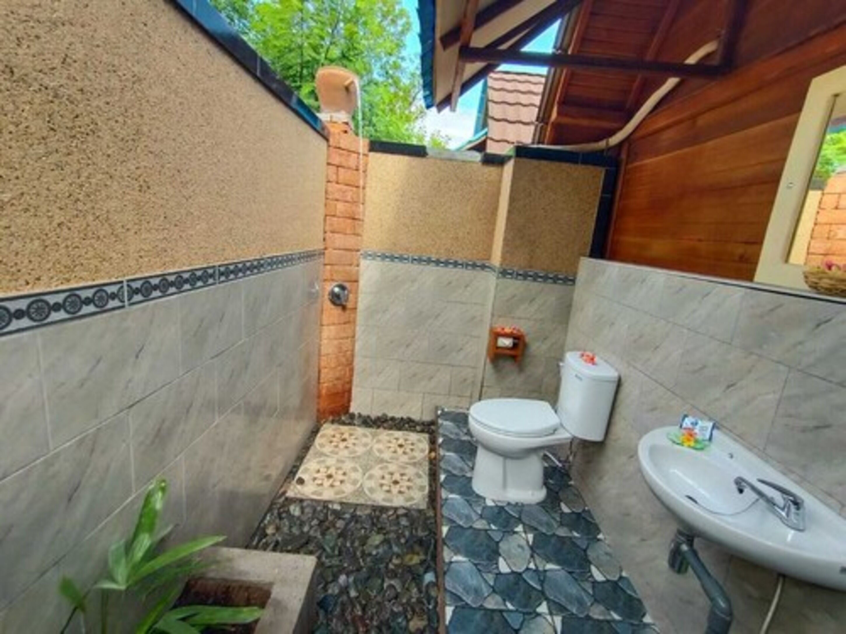 A small bathroom with a toilet, sink, and decorative tiles.