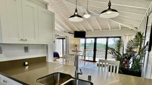 A modern kitchen with stainless steel countertops, a double sink, and pendant lighting. - Tranquility on West Moloka'i (Maunaloa)