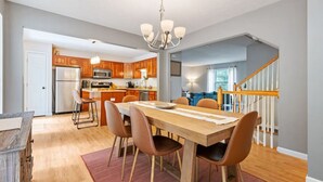 A modern kitchen with wooden cabinets, a central island, and a dining area with a wooden table and chairs. - NEW! 3 Bdrm | Mt Washington | Garage (Pittsburgh)