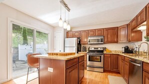 A modern kitchen with wooden cabinets, stainless steel appliances, and a large island. - NEW! 3 Bdrm | Mt Washington | Garage (Pittsburgh)