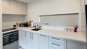 Eine moderne Küche mit weißen Schränken, einer schwarzen Arbeitsplatte und Edelstahlgeräten.