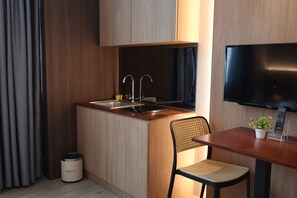 A compact kitchenette with a sink, two faucets, a microwave, and a small trash bin. - Roxy Hotel Aiman (Kota Samarahan)